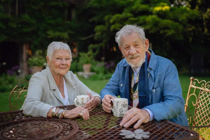 Tea With Judi Dench Dame Judi Dench and Sir Ian McKellen sat down next to each other smiling ahead in a garden.