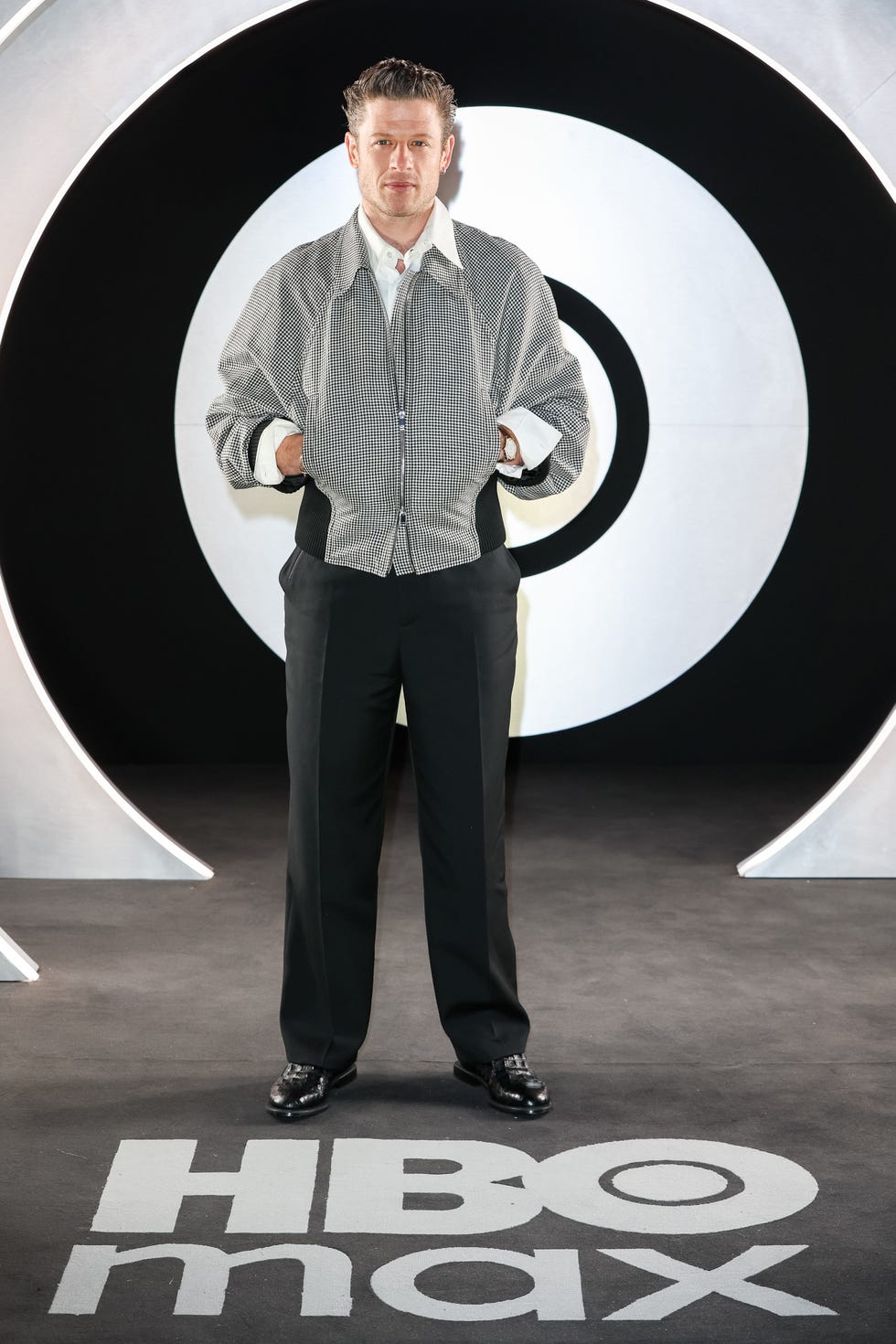james norton standing on hbo max logo backdrop at the launch event
