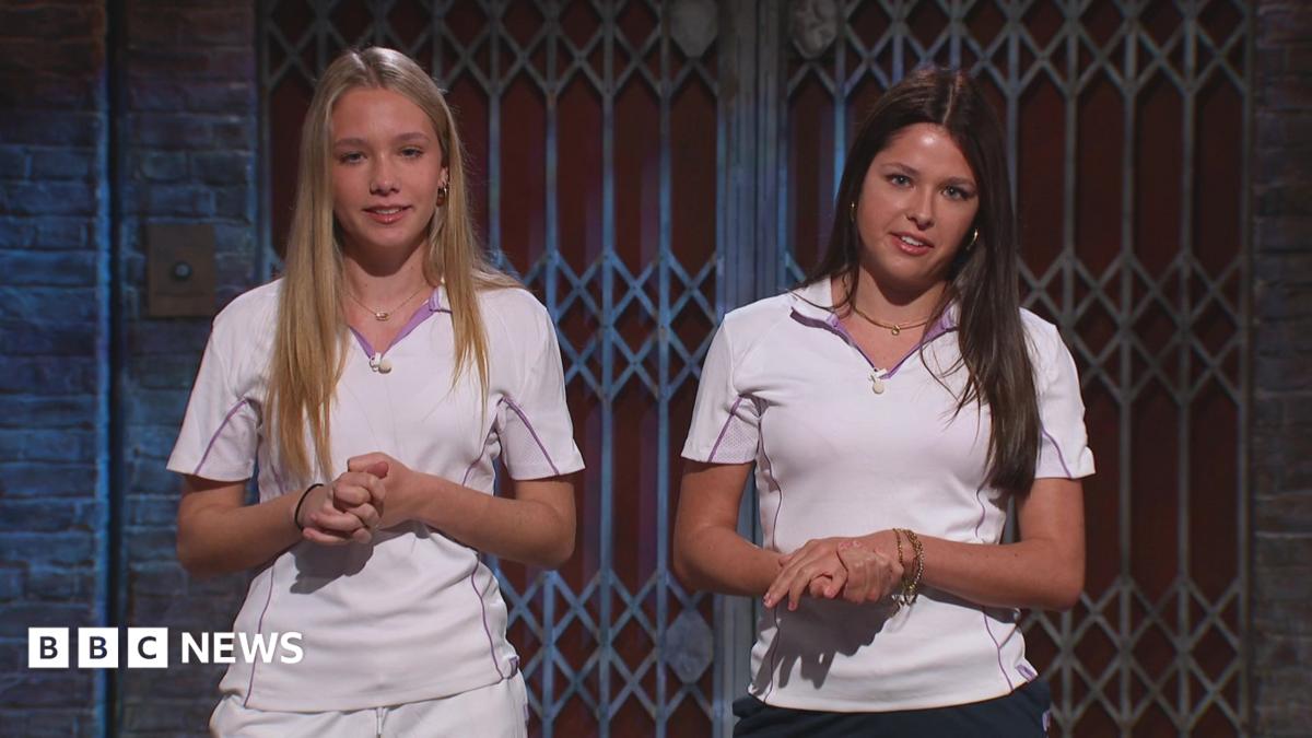 Two teenage girls wearing cricket whites. They are stood in a TV studio.