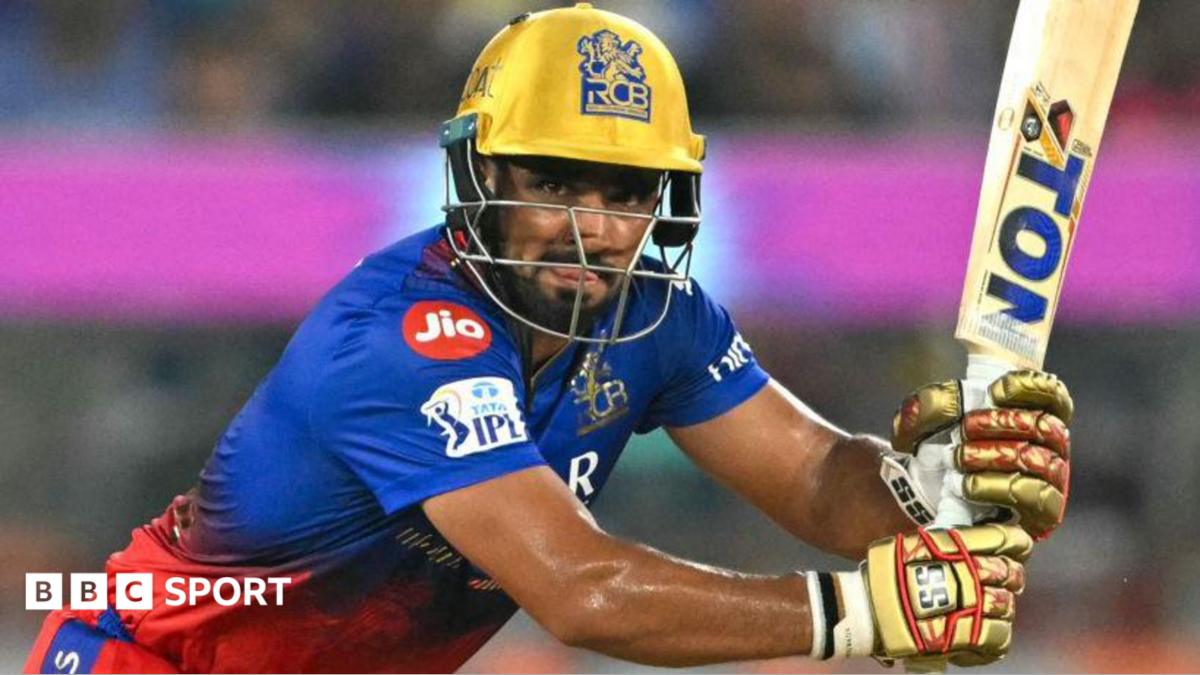 Mahipal Lomror in a blue and red shirt, with gold gloves and helmet, hits a shot with a bat facing upwards