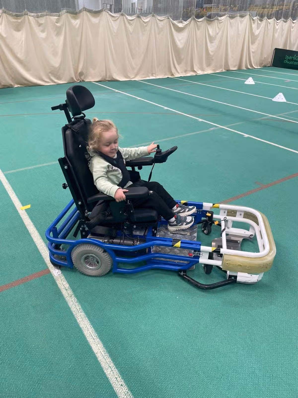 A disabled four year old plays in a wheelchair at a sports centre
