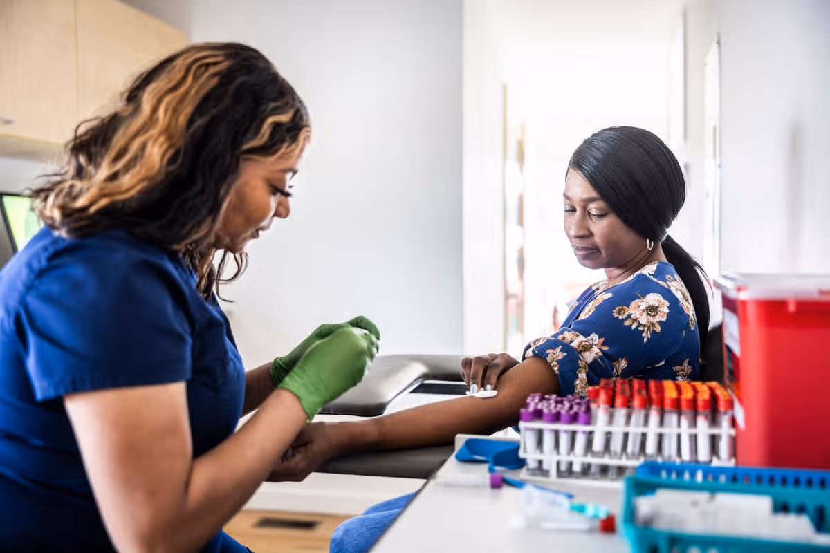 Female nurse drawing blood sample from woman in medical office