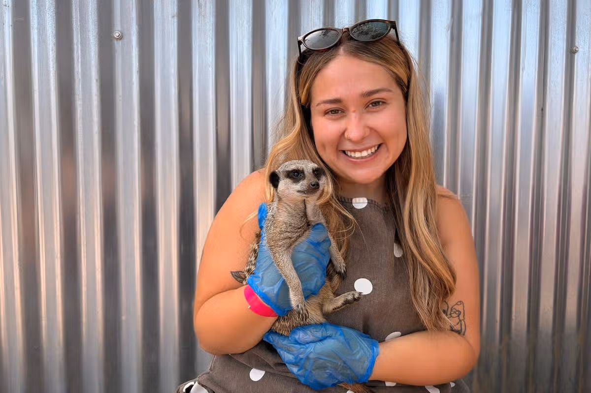 A woman holding a meerkat