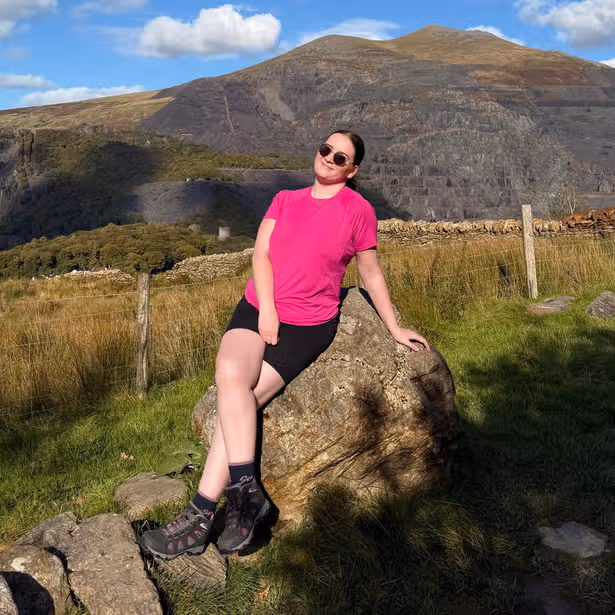 A young woman in the countryside sat on a rock