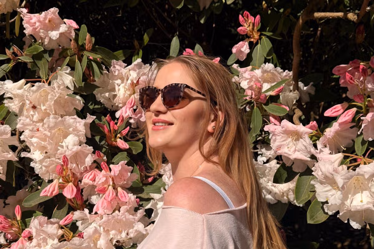 A young woman in sunglasses against a background of flowers