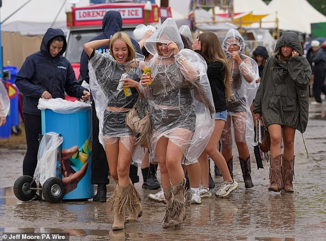 Festivalgoers sheltered from the rain in plastic ponchos yesterday as they walked through the muddy site at Reading Festival at Little John's Farm, Reading, Berkshire.
