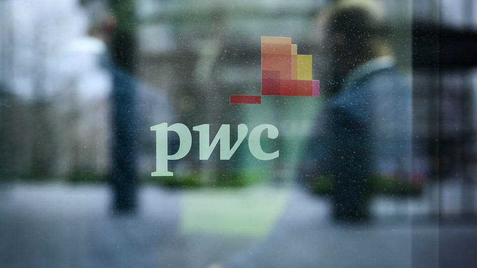 Professionals blurred walking past the PwC logo displayed on the glass exteof the firm’s London offices