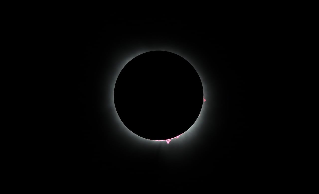 A solar eclipse, where the sun is totally covered by a black circle of the moon, with only a thin outline of light visible at the outside, is shown.