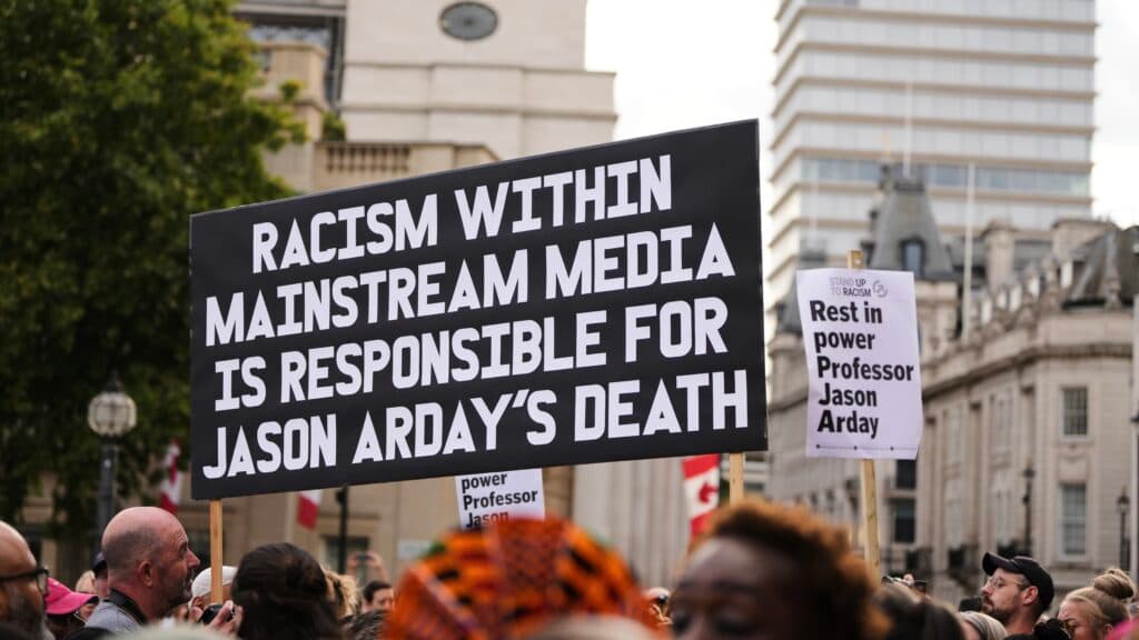 Protesters holding signs reading "Racism within mainstream media is responsible for Jason Arday's death" and "Rest in power Professor Jason Arday