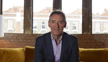 Jim ONeill, economist and former Goldman Sachs chairman, sitting on a yellow sofa in front of large windows.