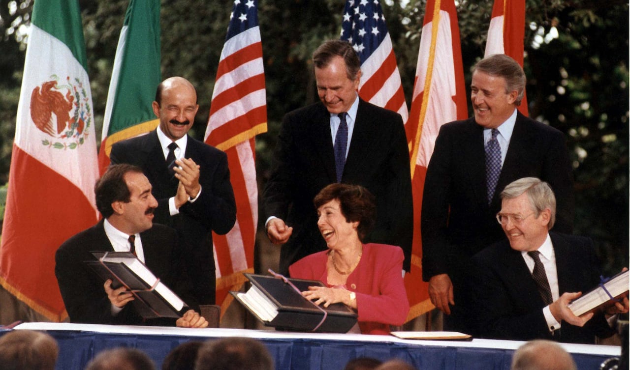 Three men in suits stand behind two men and a woman at a table.