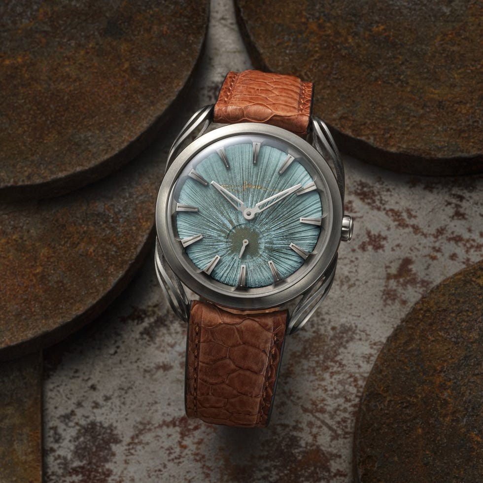 Luxury watch with a textured blue dial and brown leather strap on a rustic background. Luxury watch with a textured blue dial and brown leather strap on a rustic background.