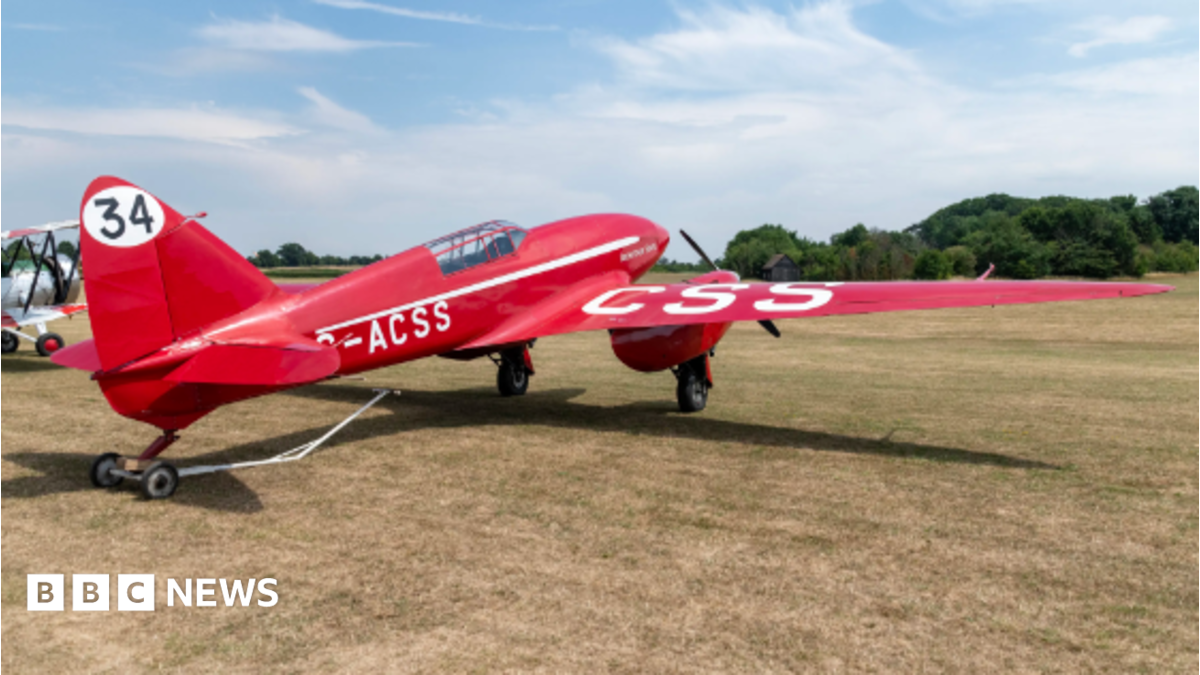 Red plane on a grass airfield. It has the number 34 painted on the tail fin.