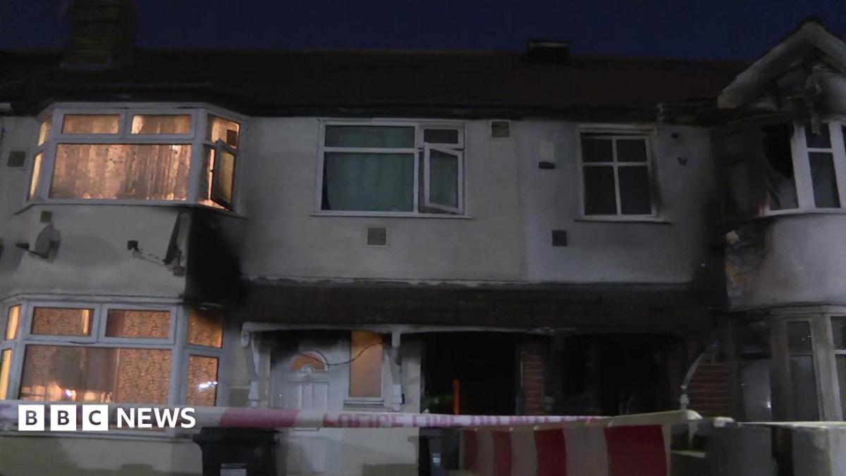 A view of a terraced-appearing house in Berkeley Avenue in Hounslow with burnt windows and some police tape at the front