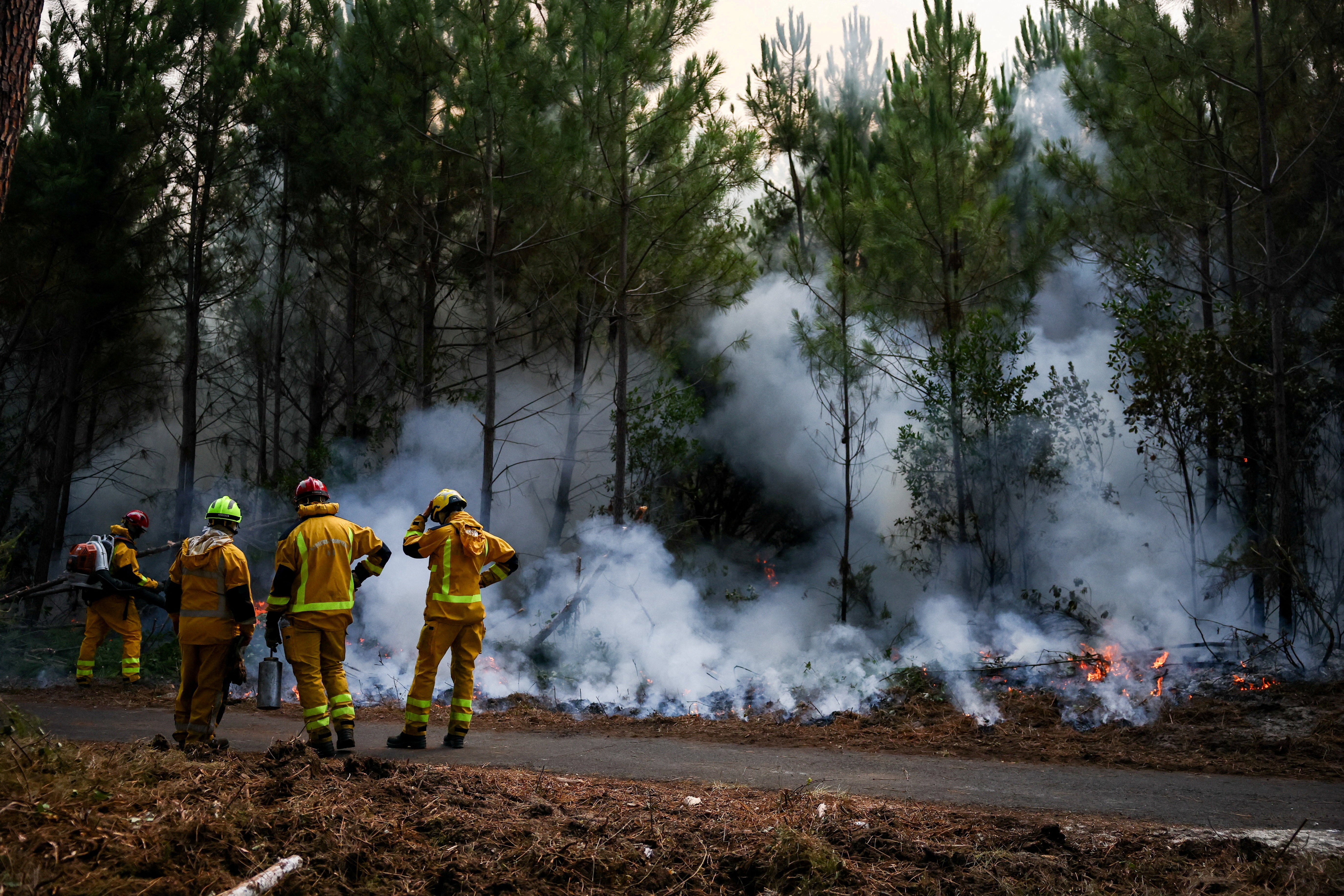 Firefighters carry out controlled burning operations in Le Porge, Gironde department