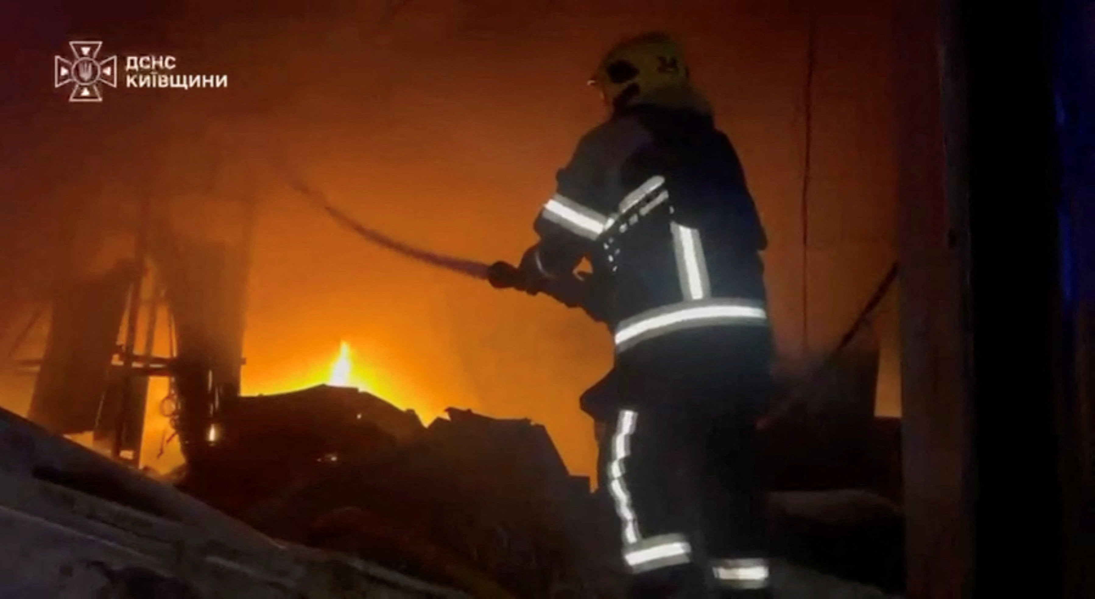 A rescuer works at the site of a fire in a warehouse at a location given as Bucha District, Kyiv Region, Ukraine, in this still image obtained from a video released on August