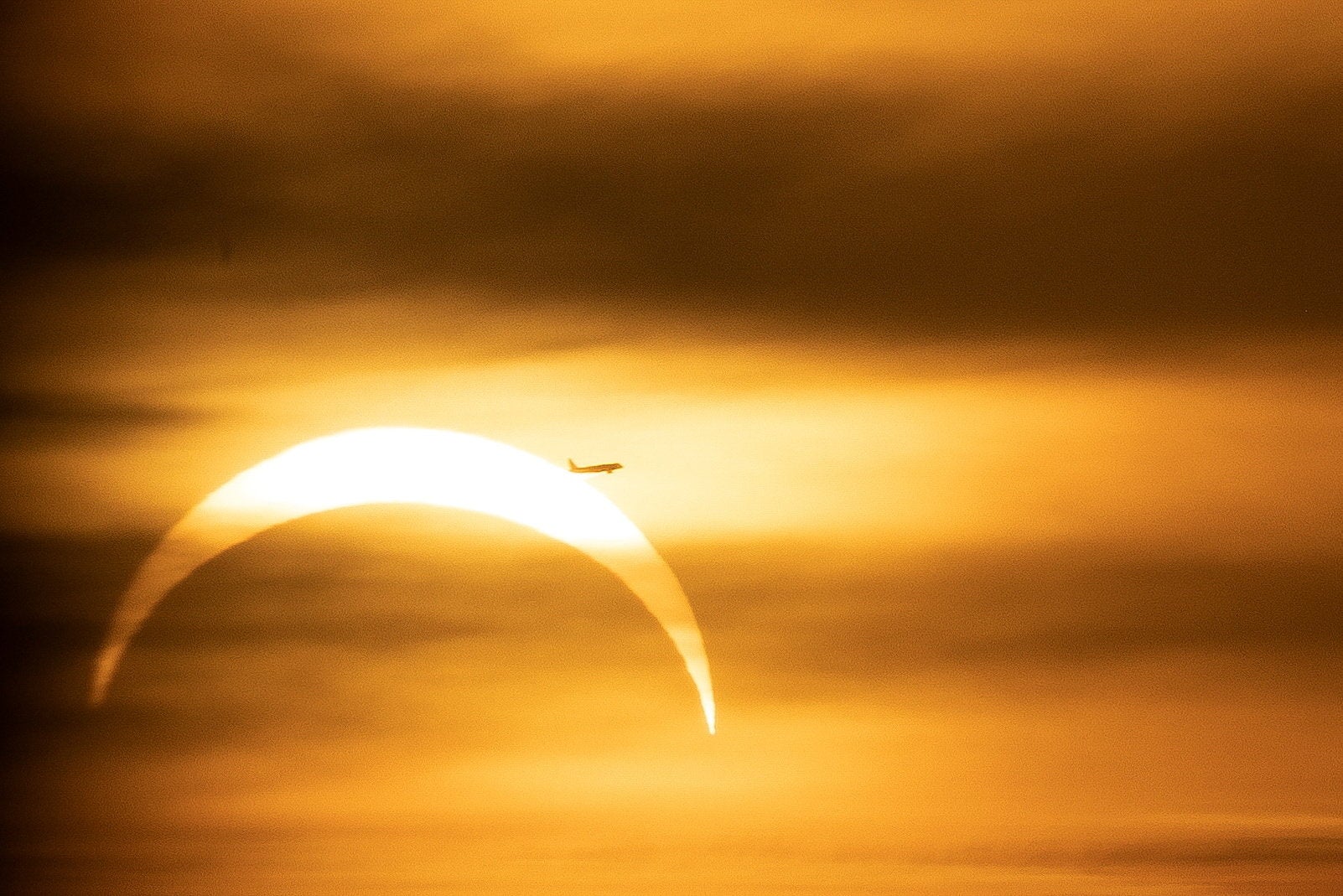 Airplane pass the sun as the moon partially covers during a solar eclipse ,as seen from Prague, Czech Republic, August 12, 2026