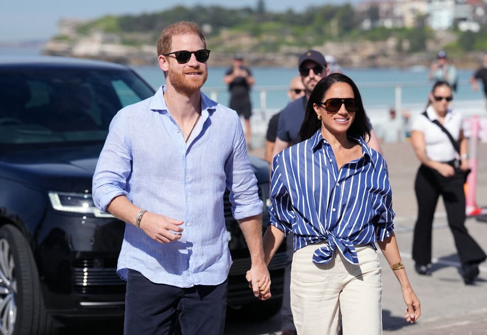 Prince Harry, Duke of Sussex, and his wife Meghan, the Duchess of Sussex walking hand in hand in in Sydney