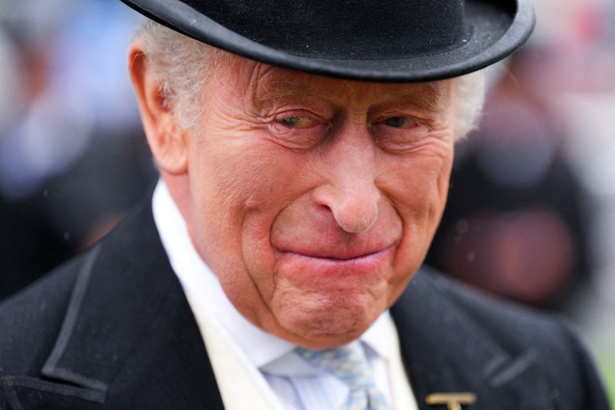 King Charles, looking on and smiling, wearing formal dress.
