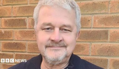 David, a man with grey hair and small grey beard, wearing a black T-shirt, looking into the camera.