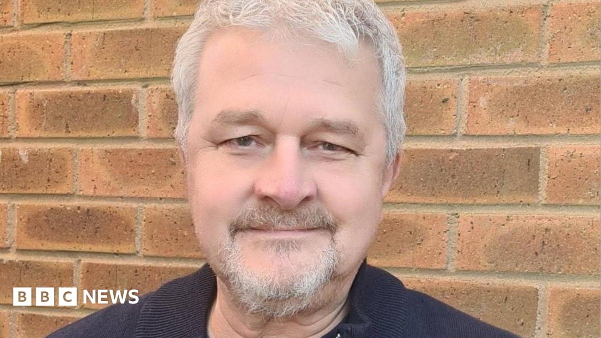 David, a man with grey hair and small grey beard, wearing a black T-shirt, looking into the camera.