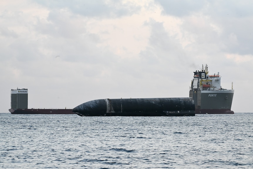 A rocket floats in the water next to a large ship