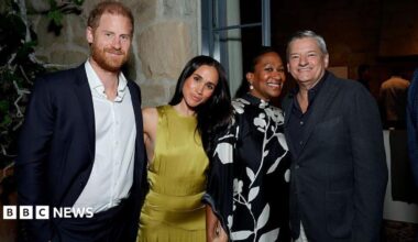 Harry and Meghan smiling next to two others, wearing cocktail attire, at a house