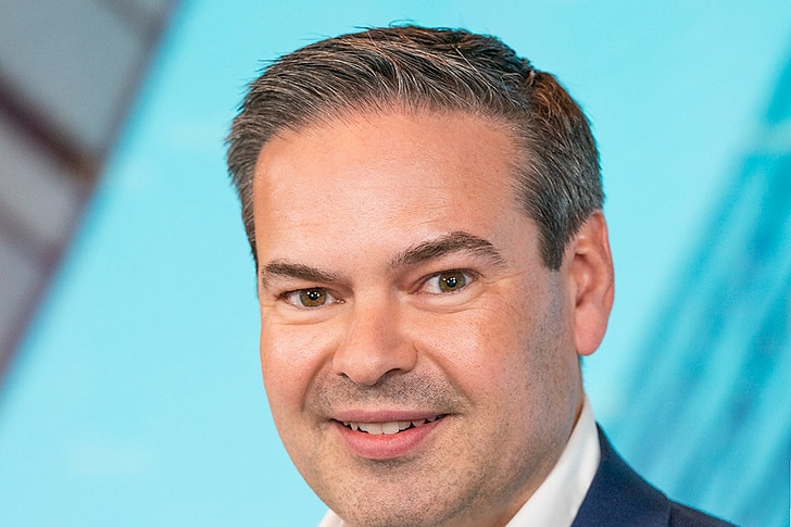 a headshot of Ryan Felsmam, a man with greying cropped hair in a navy suit jacket