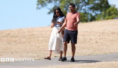 Two people walk along a scorched field in Hyde Park following a prolonged period of heat and little rainfall
