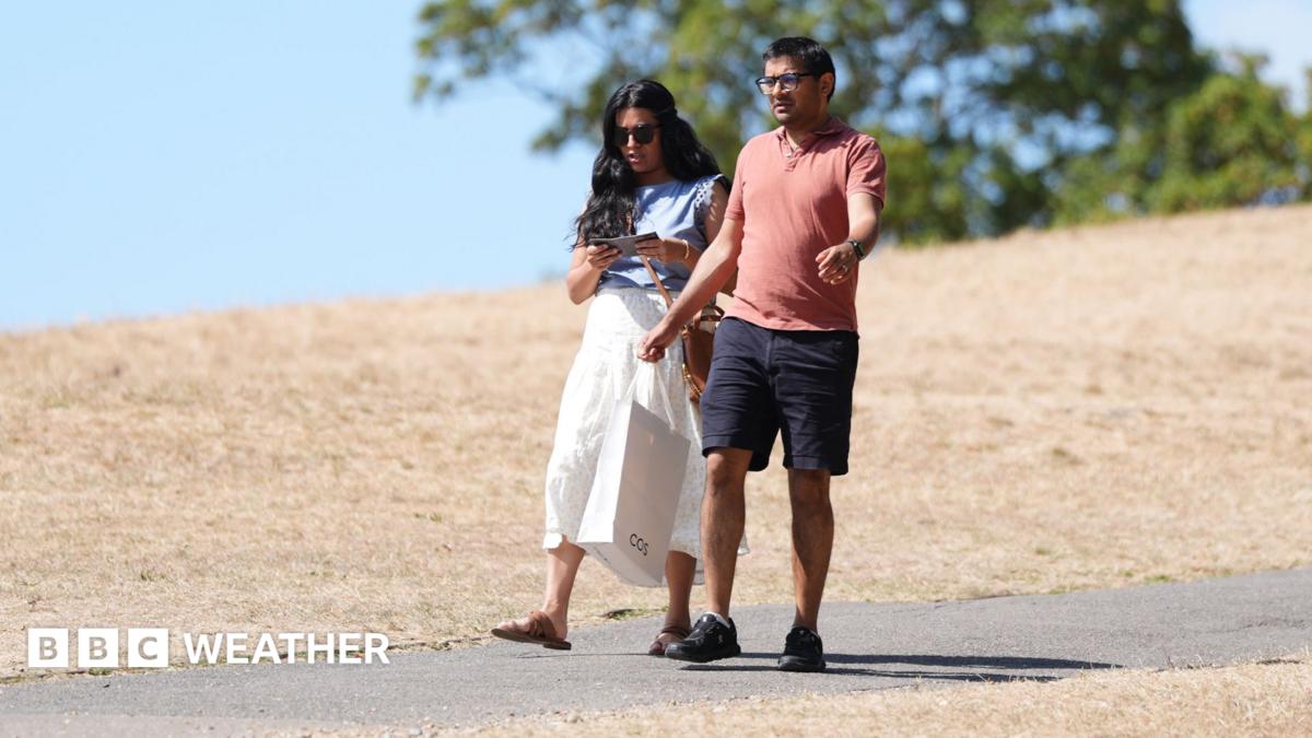 Two people walk along a scorched field in Hyde Park following a prolonged period of heat and little rainfall