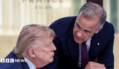 US President Donald Trump (left) speaks with Canada's Prime Minister Mark Carney during a work lunch as part of the G7 summit, in Evian, eastern France, on June 16, 2026. Trump is sitting down while Carney is standing over but leaning into the conversation.
