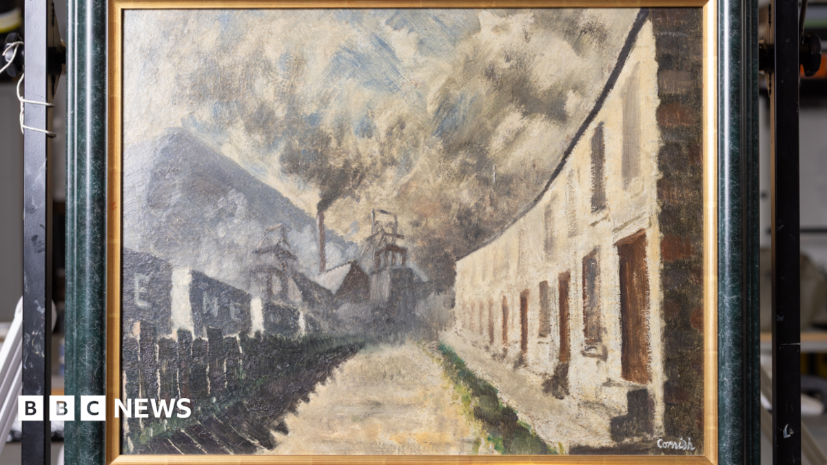 Colliery Row by Norman Cornish in a black frame with a golden edge. The paining portrays a row of terraces houses on one side, with minework buildings opposite, with smoke coming out of a large industrial chimney and the smoke filling the sky.