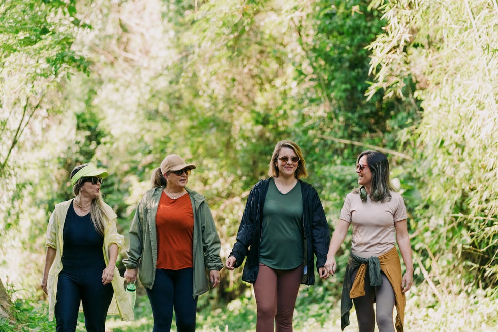 Women walking on trail women friends walking together along a green forest trail during a recreational hike.