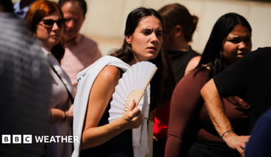 A young woman fans herself in the sunshine on a hot day