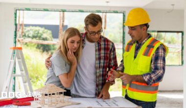 A couple looks at plans with a builder in their home, which is under renovation