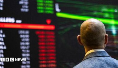 A stock marker trader looks at a large screen