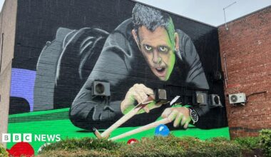 A large painted wall showing a snooker player dressed in black about to take a shot on the table