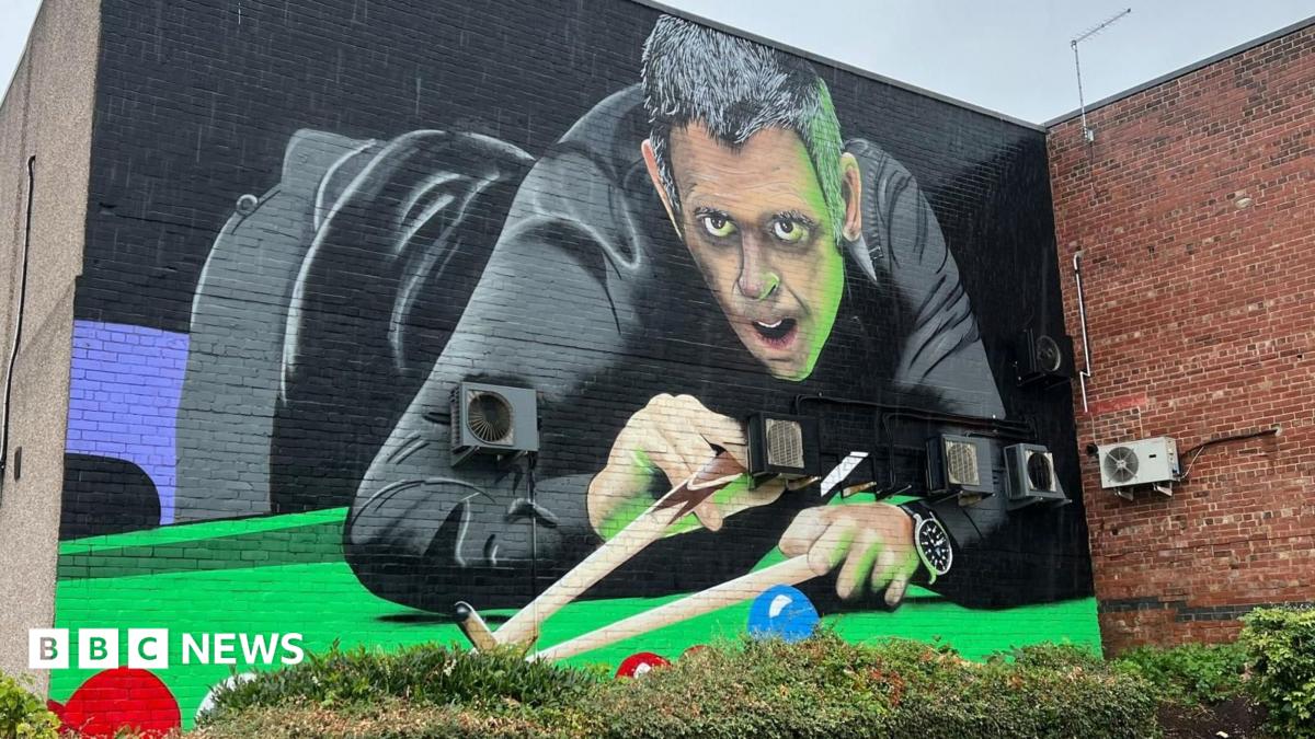 A large painted wall showing a snooker player dressed in black about to take a shot on the table