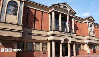 A view of Leicester Magistrates Court, a red brick building with beige stone features and a Union Jack outside