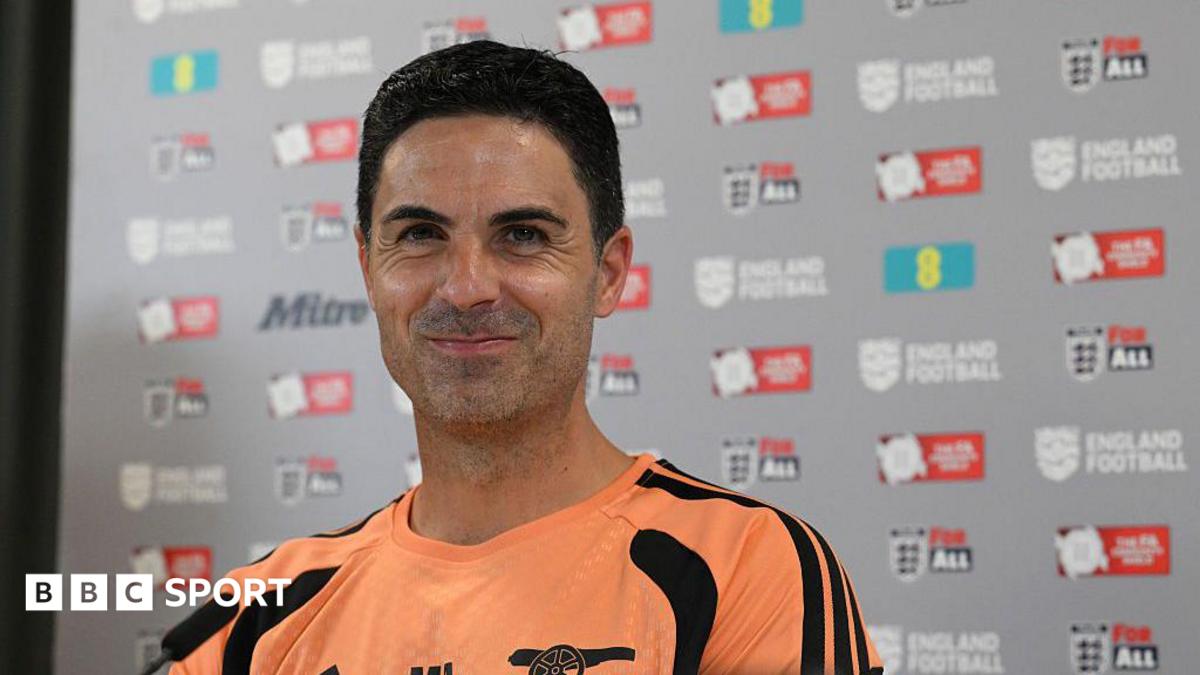 Mikel Arteta stifles a laugh while sitting at a press conference