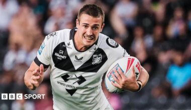 Jake Arthur runs with the ball wearing a white and black Hull FC shirt