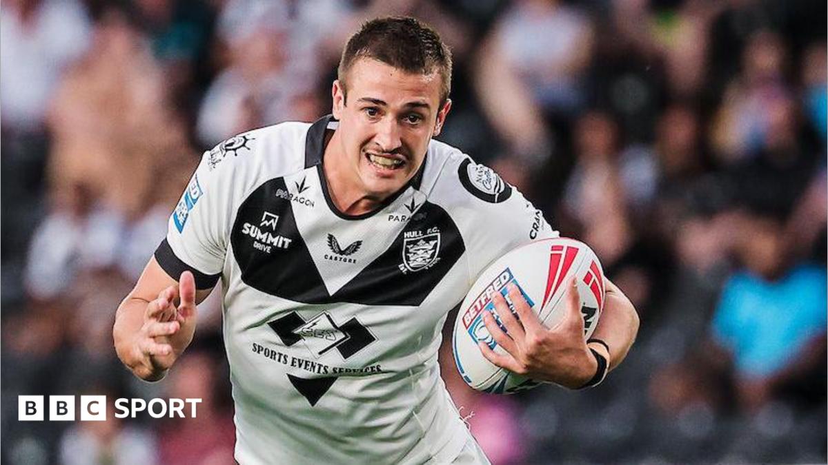 Jake Arthur runs with the ball wearing a white and black Hull FC shirt
