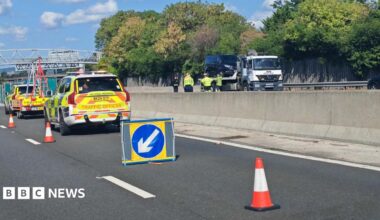 The scene of a fatal crash on the M20. There are two National Highways vehicles and a series of cones closing off the stretch of motorway. There is a tow truck on the other side of the motorway.