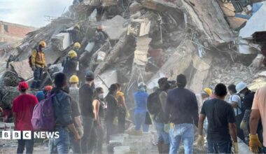 Firefighters react as they rescue a person following an earthquake, in Cali, Colombia, August 11, 2026 - one can be seen prominently in the middle, holding his arm up and appearing to shout