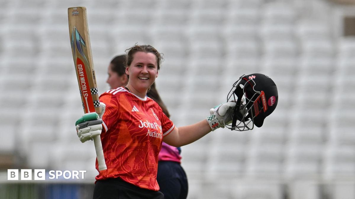 Kathryn Bryce raises her bat as she celebrates her century