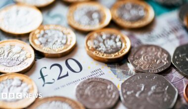 A stock image which is a close up of British cash with notes and coins. The picture includes a £20 note and a range of coins including £1 coins, 50ps and 20ps.