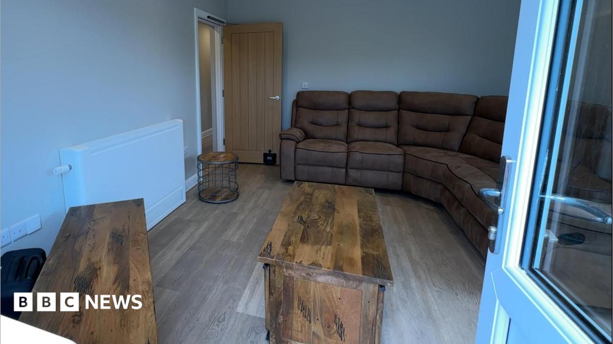 A living room with brown furniture and a wooden floor seen through the doorway from the garden