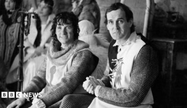 black and white image of John Cleese and Michael Palin dressed in knight's armour and looking to camera