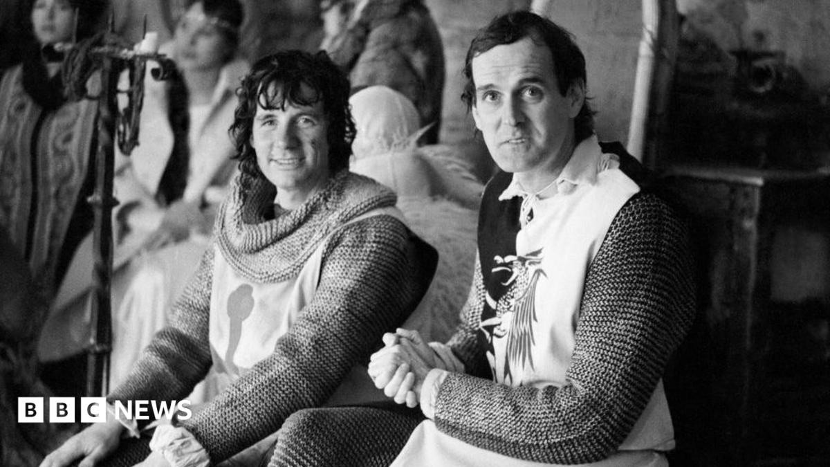 black and white image of John Cleese and Michael Palin dressed in knight's armour and looking to camera