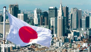 A Japanese flag flies in front of the Tokyo skyline